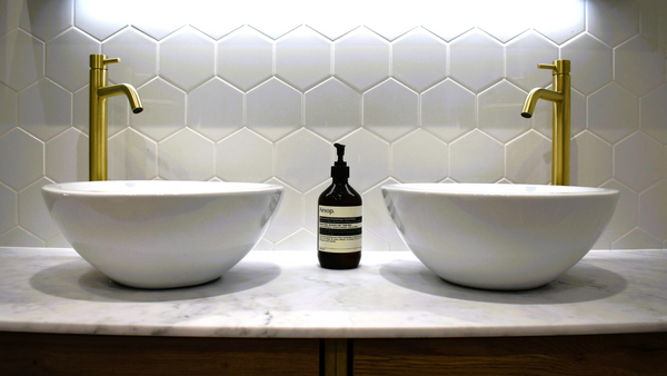 Twin Casteloni vessels with tall basin mixer taps in brushed brass with white honeycomb hexagonal tiles
