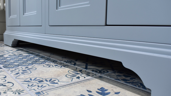 Close up of plinth of freestanding vanity unit in classic grey on blue mixed decor tiles