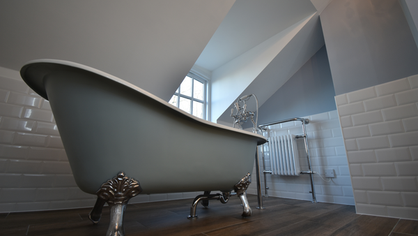 Beaulieu cast iron bath in cornflower blue with claw chrome feet against bevelled brick tiles in white and Liberty mocha porcelain floor tiles.