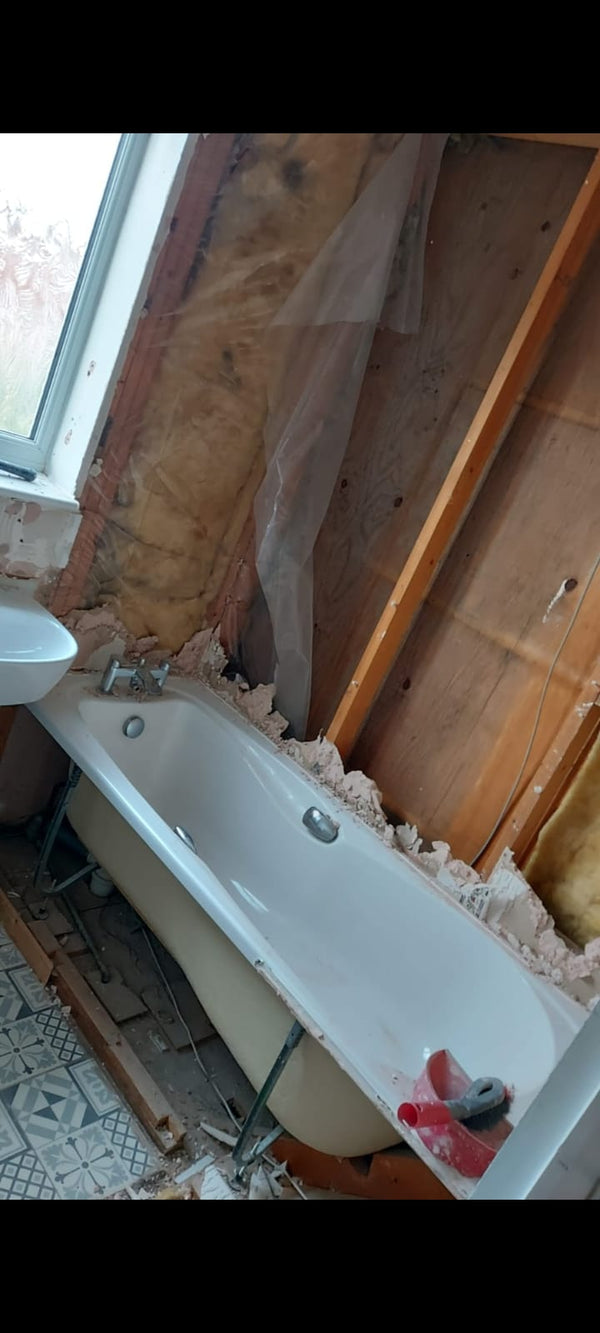 A white freestanding bath installed in a partially renovated bathroom.