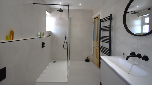 Open showering with textured tray and glass panel with black bracing bar