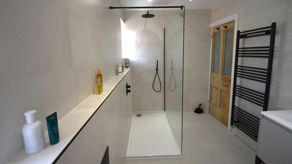 Open showering with wall to wall shower ledge and textured shower tray